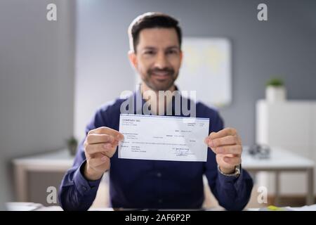 Portrait Of Mid Age Happy Businessman Offering Cheque Stock Photo
