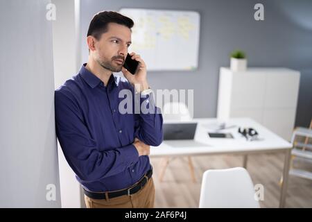 Photo Of Businessman Using Smartphone In Office Stock Photo
