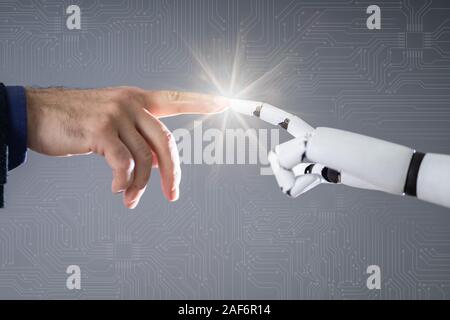 Robot Touching Human Finger Against Gray Background Stock Photo