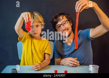 Father and son conduct chemical experiments at home. Home made slime. Family plays with a slime Stock Photo
