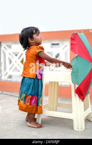 Little girl holding colorful umbrella playing in the balcony at home, Stock Photo