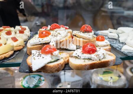 Cheese and tomato with a sprinkle of herbs on slices of bread on sale at Mercado San Miguel in Madrid, Spain. Stock Photo