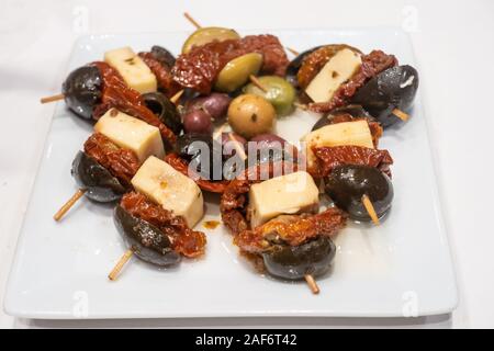 Black olives, sun dried tomato and cheese on skewers, a tapas dish. Stock Photo