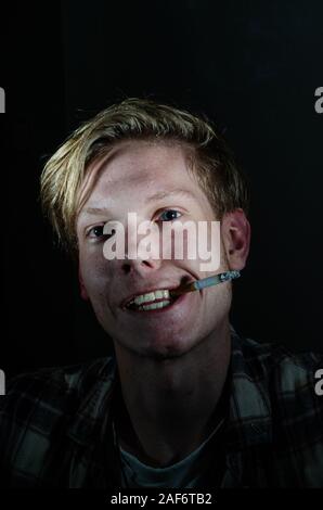 Crazy smoking man looking at the camera while having a cigarette Stock Photo
