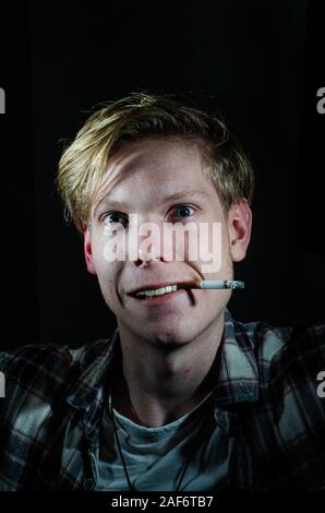 Crazy smoking man looking at the camera while having a cigarette Stock Photo