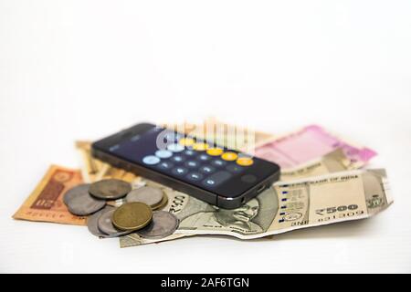 Close up view of Mobile Phone Calculate and new Indian rupees and coins Stock Photo