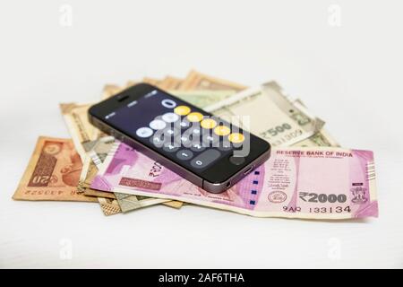 Close up view of Mobile Phone Calculate and new Indian rupees and coins Stock Photo