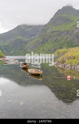 traditional wooden boats moored in clear water, shot under bright cloudy light at  A,  Lofoten, Norway Stock Photo