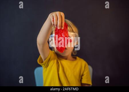 Boy playing hand made toy called slime. Child play with slime. Kid squeeze and stretching slime Stock Photo