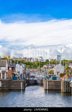 The entrance to Penarth Quays Marina in Cardiff Bay with attractive new housing architecture on the quayside and hillside beyond, Glamorgan, Wales, UK Stock Photo