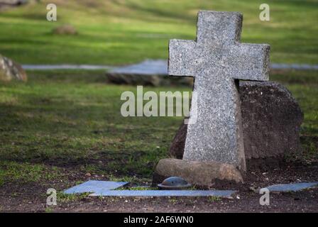 Old stone cross on the bed of honor. Memorial for those who killed during the military raides of the British Army on Koenigsberg in 1944, Kaliningrad, Stock Photo