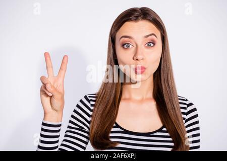 Close up photo of lovely person making v-sign wearing striped pullover isolated over white background Stock Photo