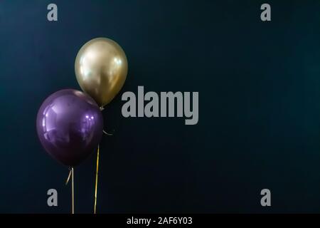 golden balloon and violet balloon on a dark background. Holiday Concept, Postcard Stock Photo