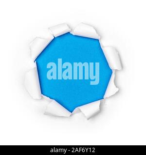 Paper hole in white paper with ragged edges with blue background. Stock Photo