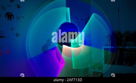 Boy playing in his room with lightsaber in various colors with figures of space invaders on the wall. Lightpaint effect Stock Photo