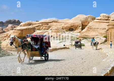 Petra, Jordan - March 06, 2019: unidentified tourists at Bab el-Siq and horse carriage in the Unesco World Heritage site of ancient Petra