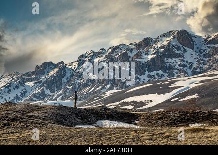 Young man standing above the highland in mountains and enjoying the view of nature Stock Photo