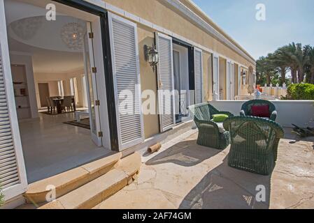 Luxury villa show home in tropical summer holiday resort with sun chairs and outdoor furniture Stock Photo
