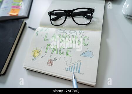 Close-up Of A Human Hand Drawing Landing Page Concept On Notebook At Desk Stock Photo