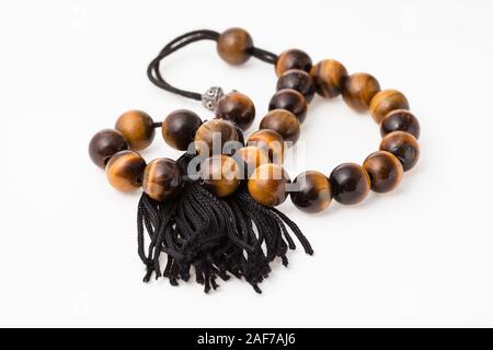 tangled worry beads from tiger's eye gemstones on white paper background Stock Photo
