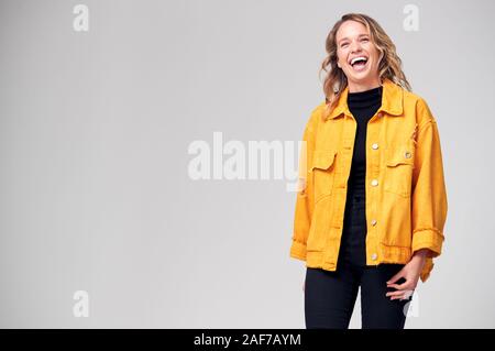 Studio Portrait Of Positive Happy Young Woman Laughing Off Camera Stock Photo