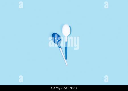 Dangerous and needed two plastic spoons. Environmental problem of plastic rubbish pollution. Flat lay, top view, copy space. Stock Photo
