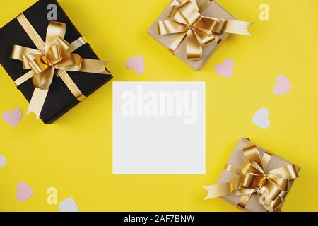Valentine's Day background. Various handmade gift boxes decorated with pink heart confetti on yellow background. Minimal style and valentines day conc Stock Photo