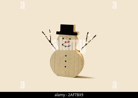 a funny wooden snowman, with a red nose and wearing a hat, on a pale brown background with some blank space around it Stock Photo