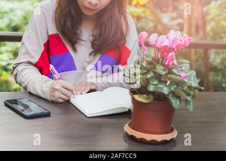 Young female hand writing notes and planning her schedule. Stock Photo