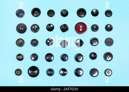 top view of red button between many black buttons on blue background Stock Photo