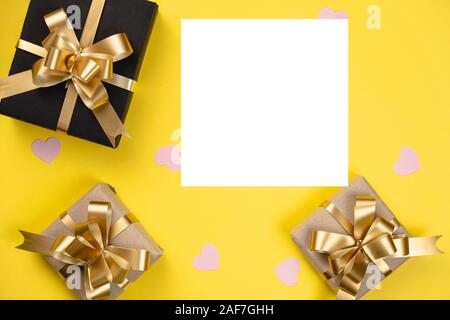 Valentine's Day background. Various handmade gift boxes decorated with pink heart confetti on yellow background. Minimal style and valentines day conc Stock Photo