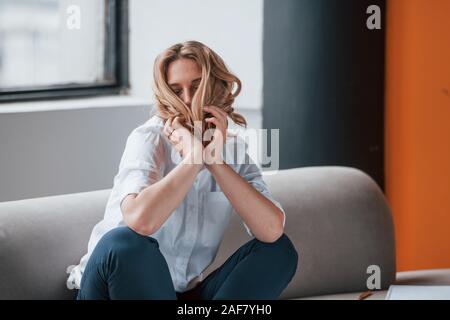 Playful mood. Businesswoman with curly blonde hair sitting in room against window Stock Photo