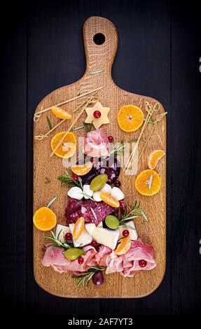 Antipasto platter with ham, prosciutto, salami, cheese and olives on a wooden background.  Christmas table. Top view, overhead Stock Photo