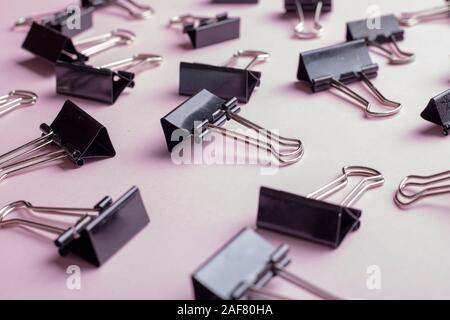 many office binder clips on pink paper Stock Photo