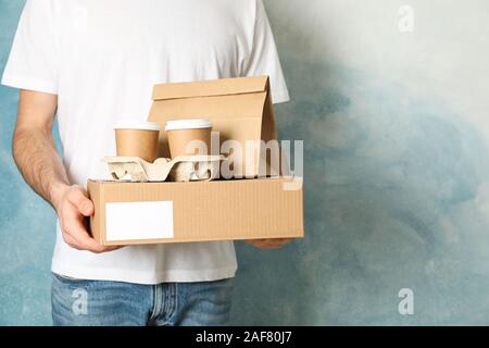 Man holds blank box, coffee cups and paper package indoor, space for text Stock Photo