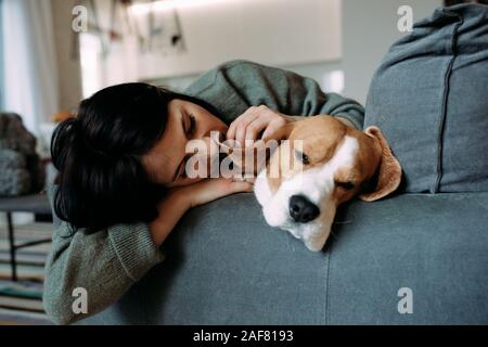 A woman and a beagle dog lie on a sofa and sleep. Closeup. Stock Photo