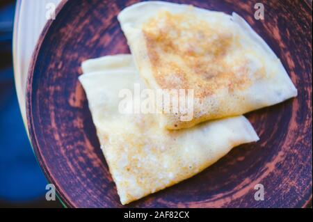 Pancakes to Maslenitsa celebration on the background of wooden boards. Pancakes on a brown plate in a cafe Stock Photo