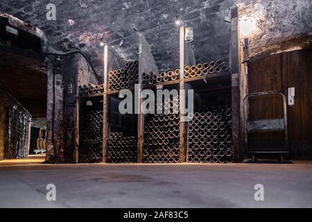 Ancient wine bottles resting, aging, dusting in underground cellar in rows. Concept winery vault with rare wines, exclusive collection. Stacks of wine Stock Photo