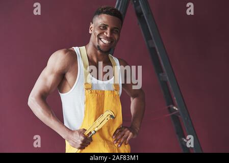Positive emotions. Young african american worker in the yellow uniform have some job Stock Photo