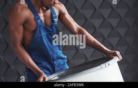 Taking barrel. Young african american worker in blue uniform have a break on his job Stock Photo