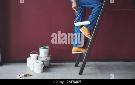 Walking up the ladder. Young african american worker in the blue uniform have some job Stock Photo