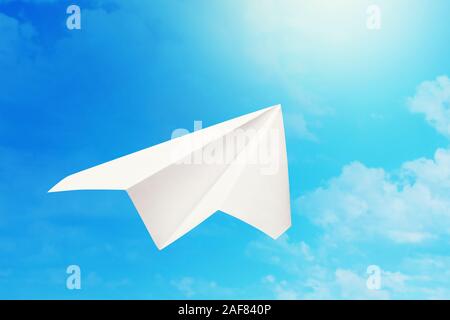 Paper plane flies to the sun against a blue sky. Concept on the topic of moving towards your goal Stock Photo