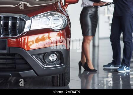 Beautiful vehicle. Assistant manager giving advices and help to the customer in automobile salon Stock Photo