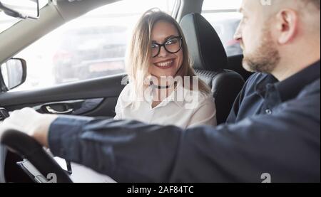 Always happy to help you. Assistant manager giving advices to the customer in automobile salon Stock Photo