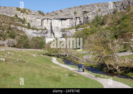 Two people walk along the footpath to Malham Cove in the Yorkshire Dales National Park Stock Photo