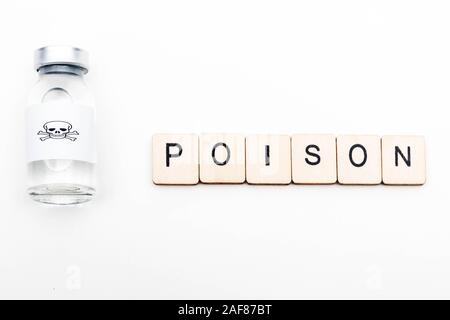 A glass medical vial with a skull and crossbones on a white background with a sign reading Poison Stock Photo
