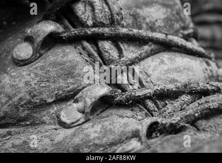 Black & white close-up shot of muddy bootlaces and eyelets on pair of tired old walking boots. Metaphor camping, hiking / hiking boots, life outdoors Stock Photo