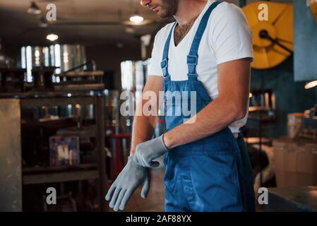 Wearing gloves. Man in uniform works on the production. Industrial modern technology Stock Photo