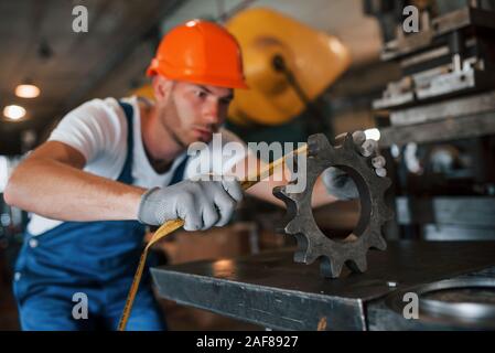 Measures the width. Man in uniform works on the production. Industrial modern technology Stock Photo