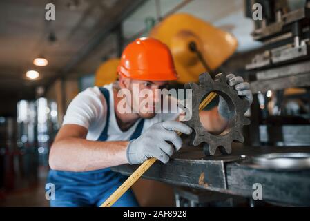 Yellow colored measuring tape. Man in uniform works on the production. Industrial modern technology Stock Photo
